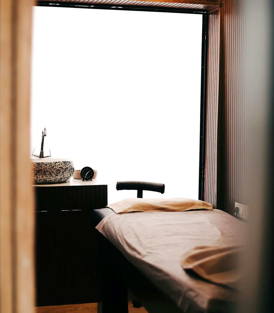 A calm treatment room with a facial bed and warm wood walls